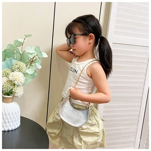 Girl wearing white ribbed vest and khaki skirt with silver pearl handle crossbody bag