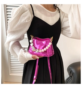 Detailed close-up of pink mini bag with pearls, heart charms and glossy metallic finish