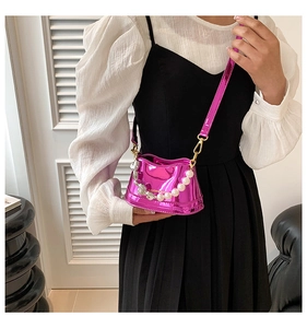 Close-up of metallic pink mini bag with pearl chain detail worn with white puff sleeve top