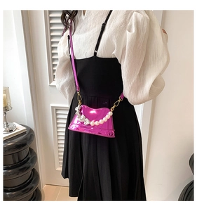 Model wearing a bright pink mini crossbody bag with pearl and silver heart chain detail