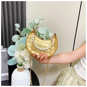 Detailed shot of a gold crescent bag with crocodile texture and elegant pearl handle