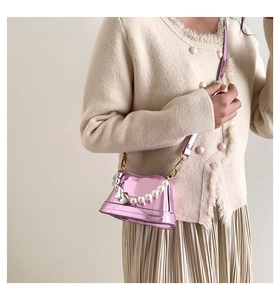 Detail of a mini metallic pink trapezoid handbag with pearl chain and heart charm