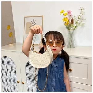 Girl modeling cream croc-effect mini bag with pearl handle and golden chain strap