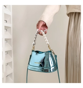 Detail of metallic blue mini bucket bag with pearl and heart-shaped chain handle