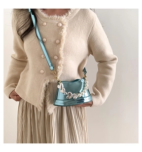 Dettaglio borsa in pelle blu metallizzata con fibbie a cuore argento e catena di perle