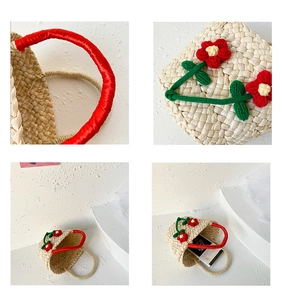 Detail of woven straw handbag with red knitted flowers and satin-wrapped handles