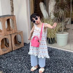 Girl's floral dress with light blue trousers and a bright pink mini basket handbag