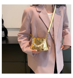 Detail of mini gold metallic crossbody bag with pearl chain and silver heart charm