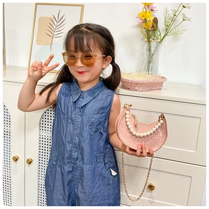 Girl wearing a pink crocodile embossed bag with large pearl handle and gold chain strap