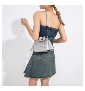 Detailed back view of silver jacket-shaped crossbody bag with metal chain strap on model