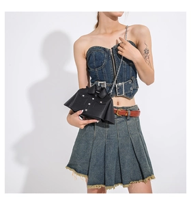 Close-up of black biker jacket style crossbody bag featuring silver chain and metal studs