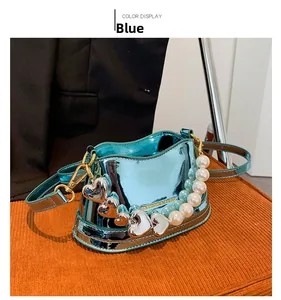Blue patent leather handbag with pearl handle and heart charms on orange chair