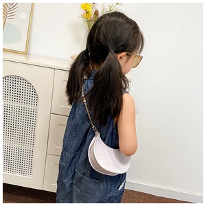 Close-up of white crocodile pattern crescent bag with gold chain on a denim outfit