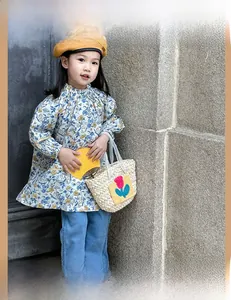 Close-up of children's beige woven straw bag featuring bright red tulip fabric patches