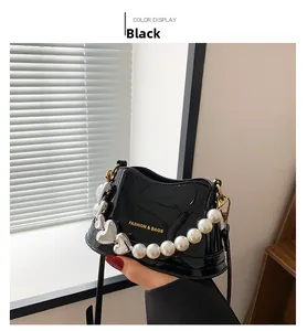 Close-up of black patent leather bag with white pearl and silver heart chain handles