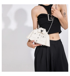 Detail view of cream white jacket-shaped crossbody bag with silver chain strap