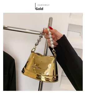 Detailed shot of a gold metallic handbag with large pearl handle and silver chain strap