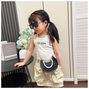 Detail of child's black crocodile texture mini bag with elegant pearl handle and gold chain