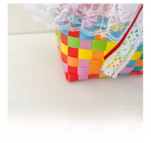 Detail showing rainbow woven basket texture with white lace edging and red ribbon trim