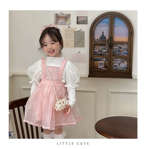 Detailed view of girls' pink tutu dress paired with white blouse and pearl handbag