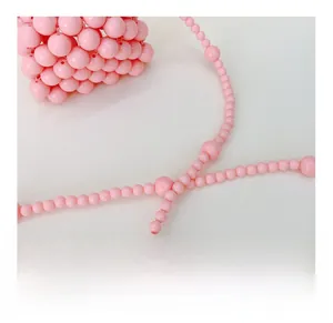 Dettaglio ravvicinato della borsa rosa fatta a mano con tracolla decorata di perline