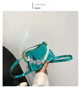 Detail of green patent leather crossbody bag with white pearls and silver heart charms
