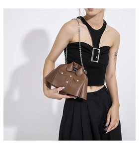 Detail of creative blazer-shaped brown leather handbag with collar and silver chain strap