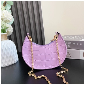 Detail of purple croc-embossed crescent mini bag with gold chain strap on home decor background