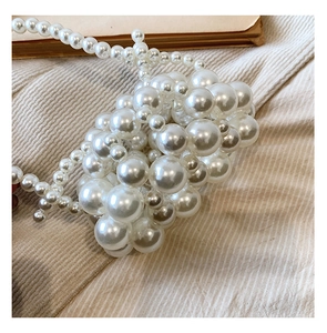 Macro shot of elegant cream faux pearl weaving and vintage beaded texture on handbag