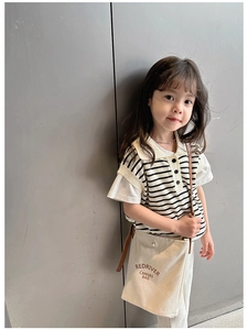 Détail d'une fille portant un sac à bandoulière en toile crème avec lettrage rouge sur une veste