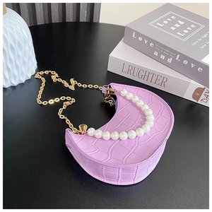 Detail of purple crescent bag featuring crocodile texture and elegant pearl handle