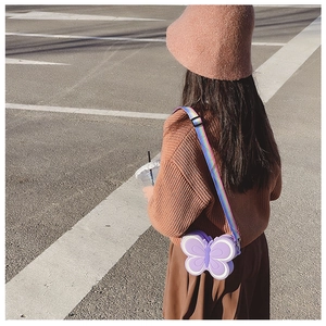 Detail showing a purple butterfly silicone crossbody bag with a rainbow woven strap