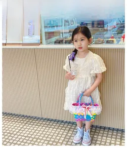 Detail of colorful woven girl's handbag with lace trim and red ribbon bow accent