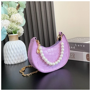 Detail of lavender faux-crocodile handbag with elegant pearl handle and gold chain