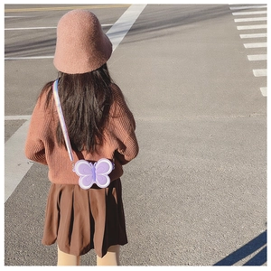 Detail of a purple butterfly silicone kids bag with rainbow strap worn by a child