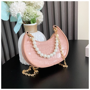 Detail of pink faux crocodile leather mini bag with large pearl handle and gold chain strap