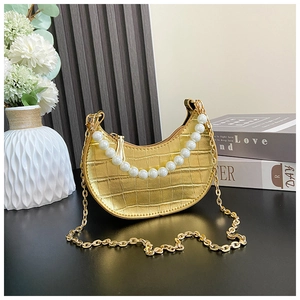 Detail of gold crescent bag with crocodile texture, pearl handle and metal chain
