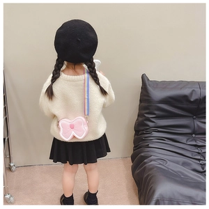 Pink silicone bow-knot crossbody bag with rainbow strap worn by a young girl