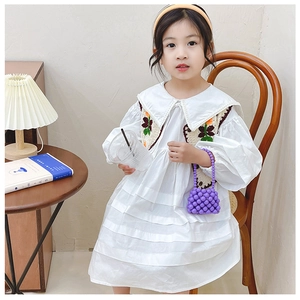 Dettaglio del gilet a fiori all'uncinetto e vestito bianco a balze per bambina