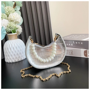 Detail of silver crocodile pattern crescent bag with pearl handle and gold chain