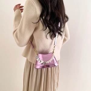 Mini metallic pink crossbody bag with pearls and silver heart charm on model