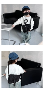 Détail du sac bandoulière noir pour enfant en nylon avec rabat et patch tendance