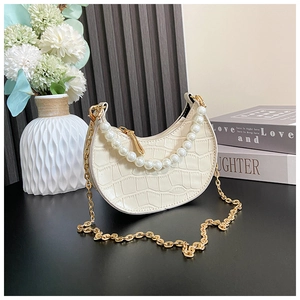 Close-up of cream semi-circle kids bag with pearl handle and golden chain strap