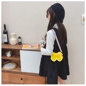 Detail of yellow silicone bow bag with colorful rainbow strap on a young child