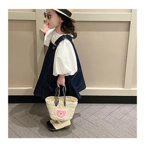 Kids flower straw tote bag paired with a white blouse and navy blue denim overall dress