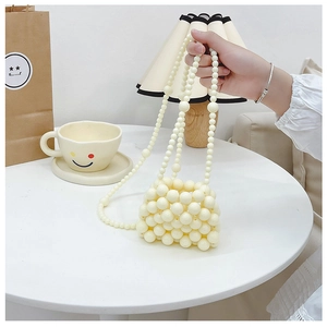 Dettaglio della mini borsa in perle crema con elegante catena a tracolla lunga