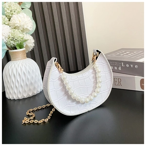 Detail of white crocodile pattern crescent bag with pearl handle and gold chain strap