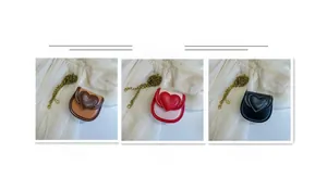 Trois mini sacs bandoulière en forme de cœur en beige, rose et noir avec chaînes en bronze