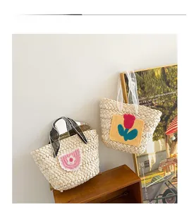 Detail of woven straw bags featuring floral patches and lace ribbon handles