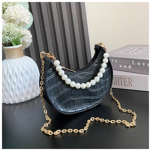 Detail of black faux crocodile pattern kid bag with large pearl handle and chain